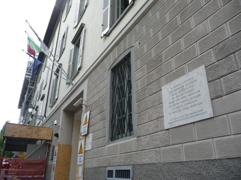 Lapide commemorativa al Convitto Baroni in memoria delle vittime di tortura. Edificio storico con bandiere.