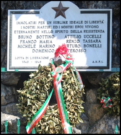 Lapide commemorativa ai caduti per la Libertà a San Marcellino, adornata con un omaggio floreale.