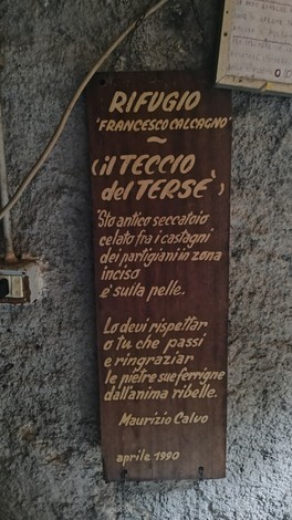 Interno del rifugio "Francesco Malcagni" con un'insegna in legno che testimonia la storia partigiana.