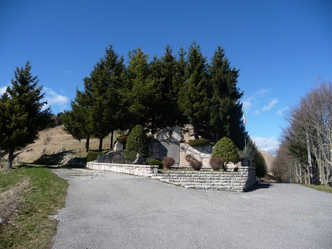 Monumento ai Partigiani al Colletto, immerso nel verde, con una strada che conduce all'ingresso circondato da alberi.