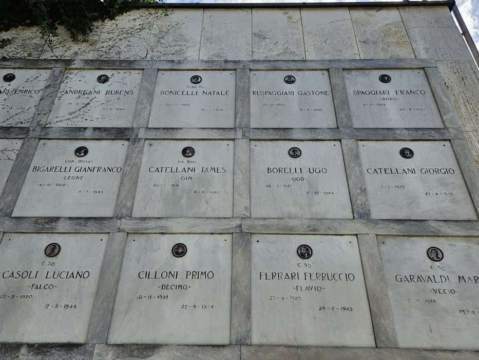 Monumento ai Caduti Partigiani, con targhe commemorative dei combattenti. Atmosfera di rispetto e memoria storica.