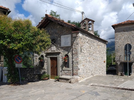 Lapide commemorativa su una facciata di una chiesa in un pittoresco villaggio di montagna.