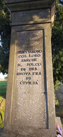 Monumento ai caduti dell'Amola, con iscrizioni commemorative su una colonna di pietra.
