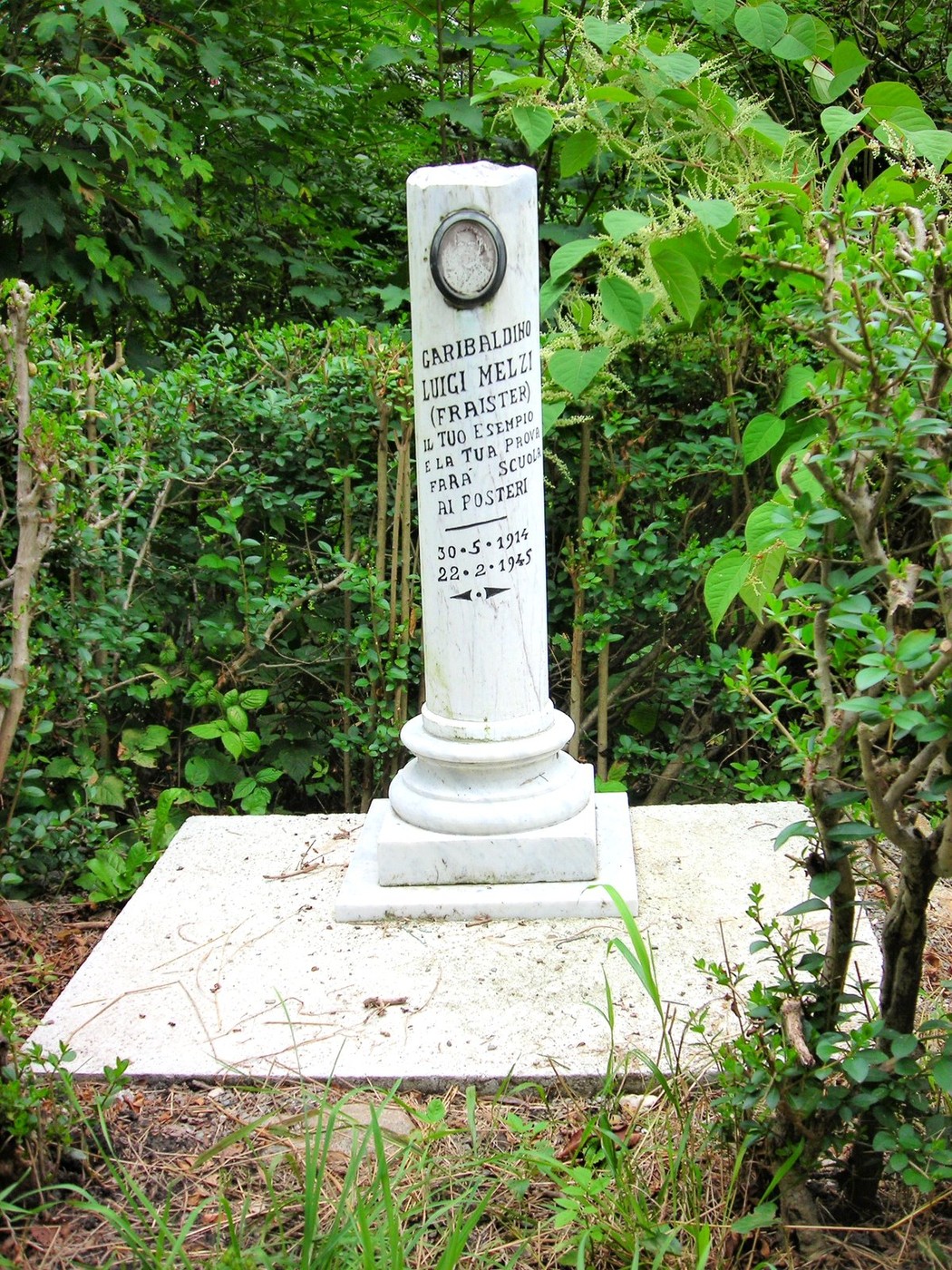 Cippo commemorativo dedicato a Luigi Melzi, situato in un'area verde. Rappresenta la memoria storica locale.